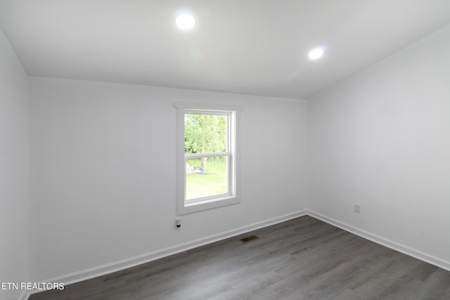 empty room with dark wood-style floors, visible vents, baseboards, and recessed lighting