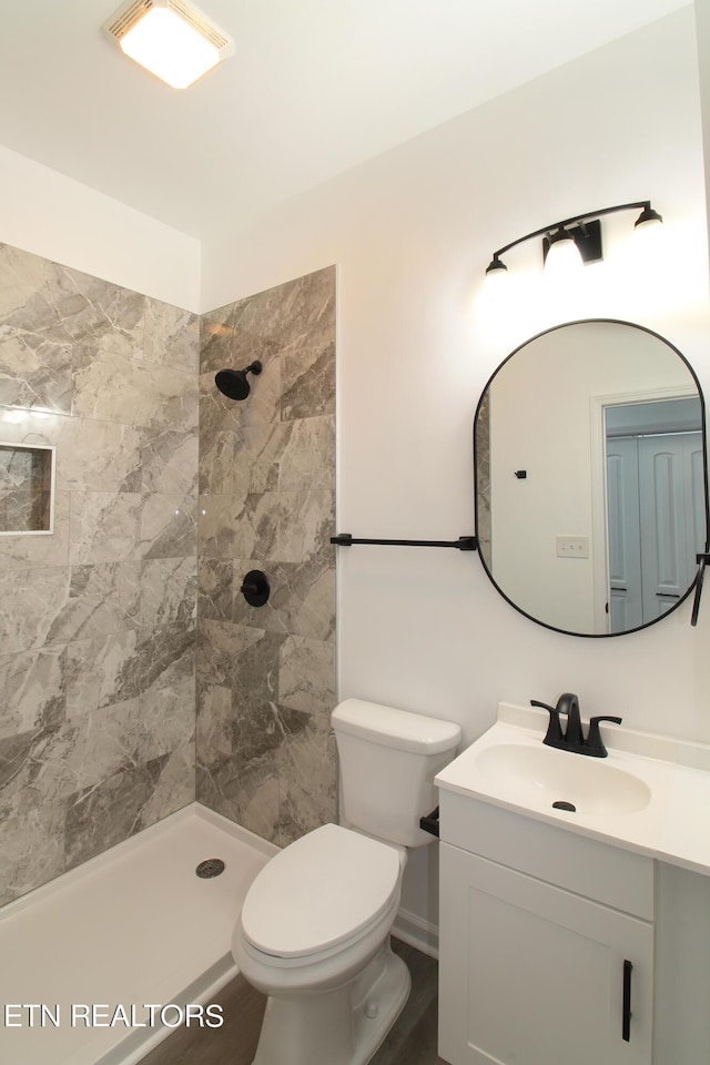 bathroom featuring tiled shower, vanity, and toilet