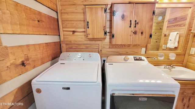 laundry area featuring independent washer and dryer, wooden walls, and sink