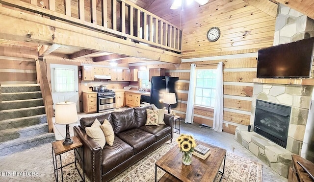 living room featuring a fireplace, wooden walls, and a high ceiling