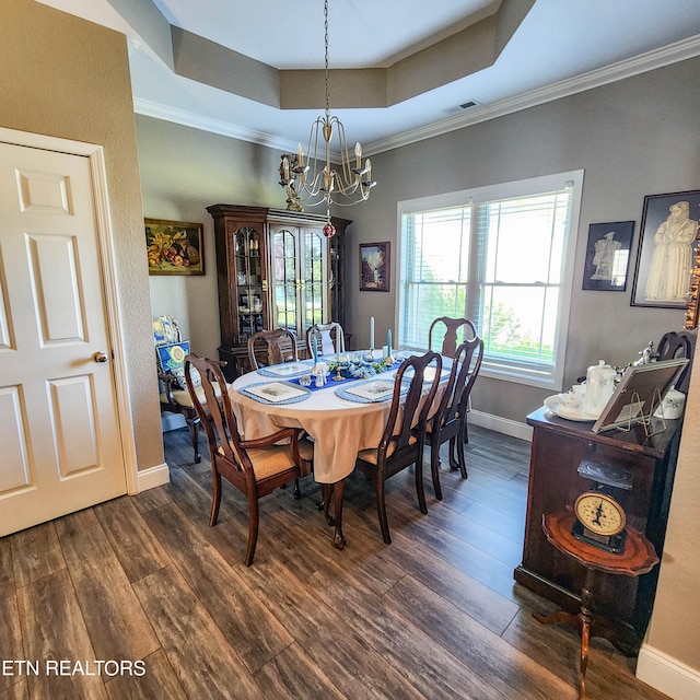 dining area with crown molding, dark hardwood / wood-style floors, a chandelier, and a raised ceiling