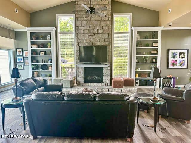 living room featuring lofted ceiling, a fireplace, wood-type flooring, and ceiling fan