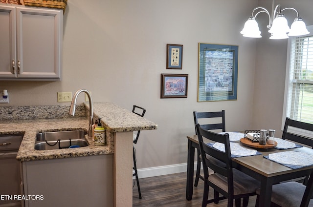 dining area with an inviting chandelier, sink, and dark hardwood / wood-style floors