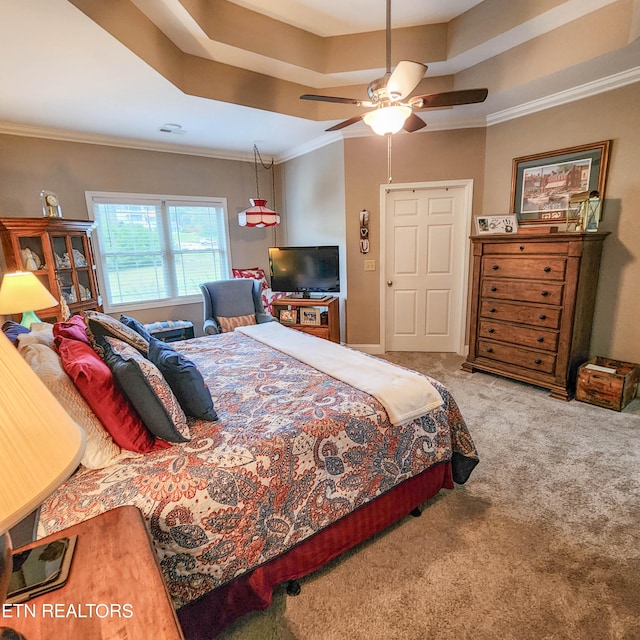 carpeted bedroom with ceiling fan, ornamental molding, and a tray ceiling