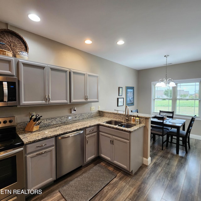 kitchen featuring kitchen peninsula, dark hardwood / wood-style flooring, appliances with stainless steel finishes, pendant lighting, and sink