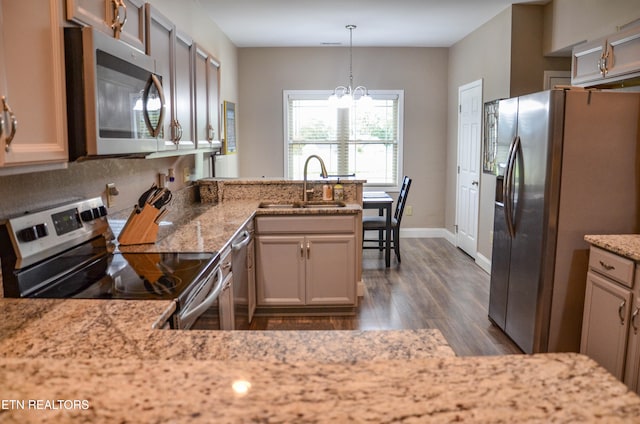 kitchen with sink, dark hardwood / wood-style flooring, kitchen peninsula, stainless steel appliances, and decorative light fixtures