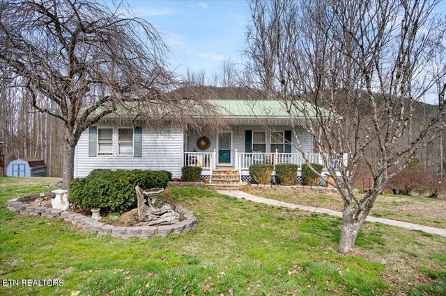 ranch-style house featuring a front yard, an outdoor structure, and covered porch