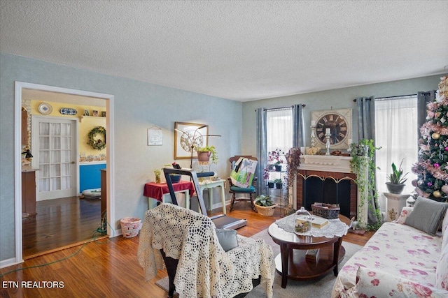 living room featuring hardwood / wood-style floors, a textured ceiling, and a brick fireplace