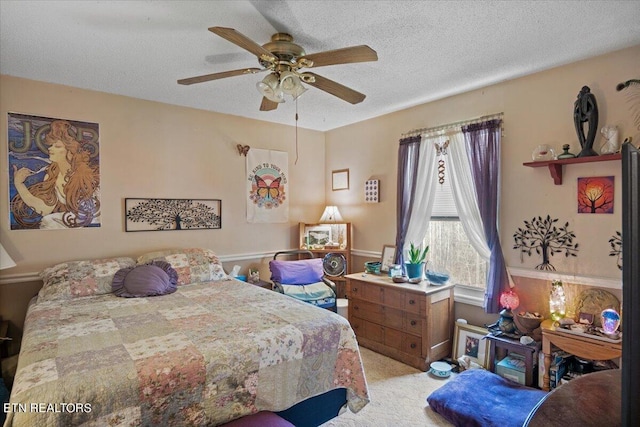 bedroom with a ceiling fan, a textured ceiling, and light colored carpet