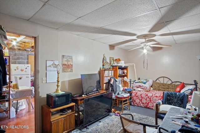 living area with a drop ceiling and a ceiling fan