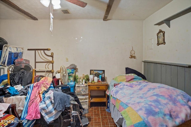 bedroom with brick floor, a wainscoted wall, visible vents, a ceiling fan, and a textured ceiling