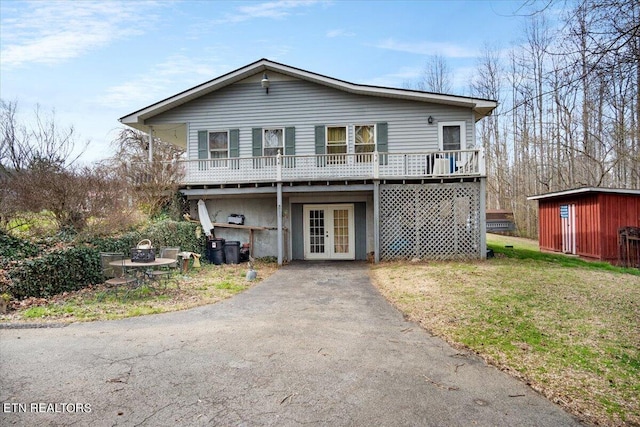 view of front of property featuring an outbuilding, a storage shed, french doors, a wooden deck, and a front yard