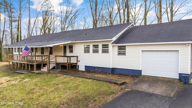 view of front of property featuring roof with shingles, a front yard, a garage, driveway, and a wooden deck