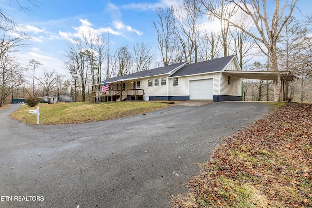 ranch-style home with an attached carport, driveway, an attached garage, and a front yard