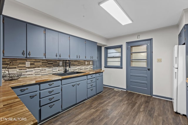 kitchen featuring blue cabinetry, wood counters, decorative backsplash, and a sink