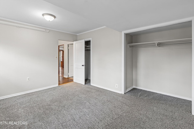 unfurnished bedroom featuring carpet floors, ornamental molding, multiple closets, and baseboards