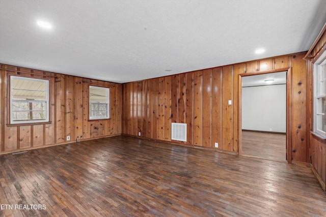 unfurnished room with hardwood / wood-style flooring, visible vents, and baseboards