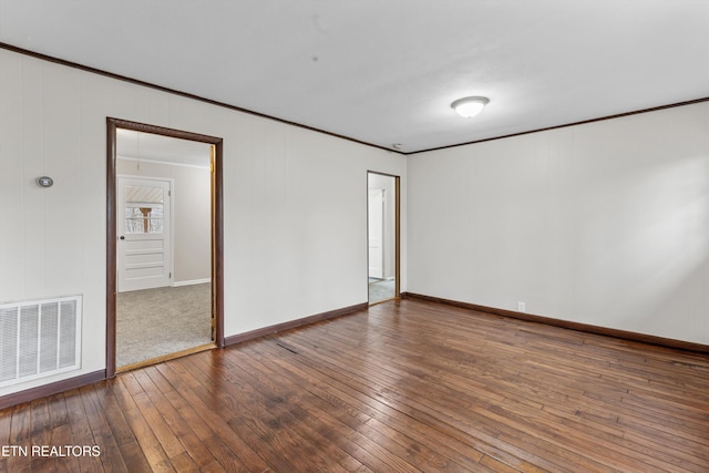 empty room featuring baseboards, wood-type flooring, visible vents, and crown molding