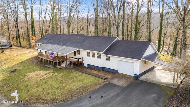 view of front of home with driveway, a garage, roof with shingles, a wooden deck, and a front lawn