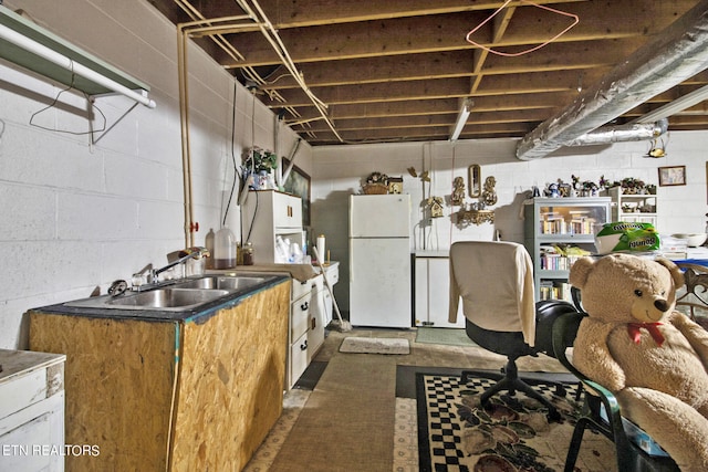 unfinished below grade area featuring fridge, a sink, and freestanding refrigerator