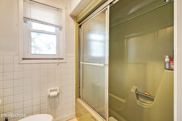 full bath featuring shower / bath combination with glass door, tile walls, and toilet