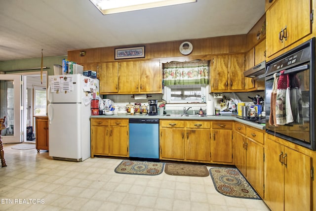 kitchen featuring brown cabinets, under cabinet range hood, stainless steel appliances, light floors, and a sink