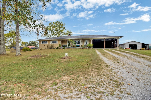 ranch-style home featuring a carport, a front yard, and an outbuilding