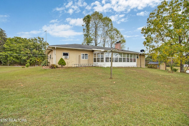 view of front of house featuring stucco siding, a chimney, a sunroom, and a front yard