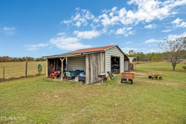 view of pole building with driveway, a lawn, and a rural view