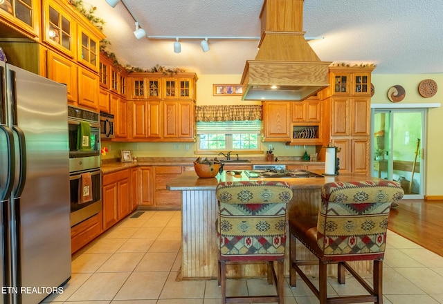 kitchen with light tile patterned floors, appliances with stainless steel finishes, premium range hood, and a sink