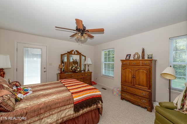 bedroom with light colored carpet, ceiling fan, and multiple windows