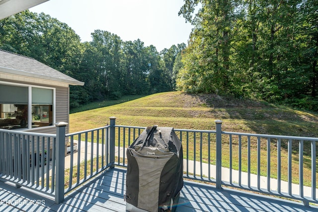 wooden terrace featuring a yard and a grill