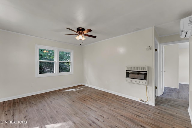 unfurnished room featuring a glass covered fireplace, ornamental molding, wood finished floors, a wall mounted air conditioner, and heating unit