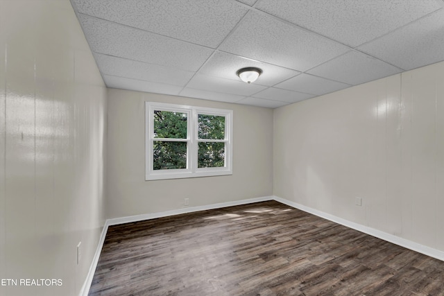 spare room featuring a paneled ceiling, baseboards, and wood finished floors