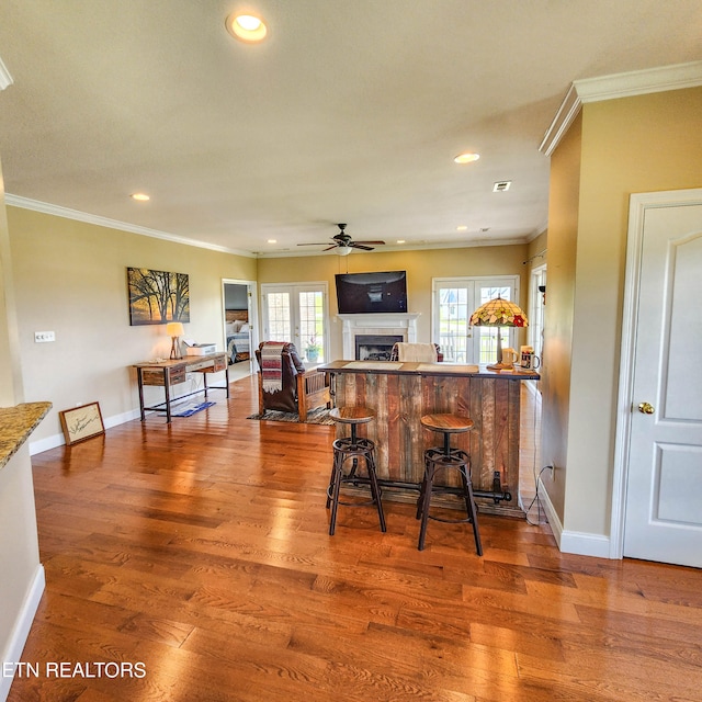 kitchen with hardwood / wood-style flooring, a breakfast bar area, and ornamental molding