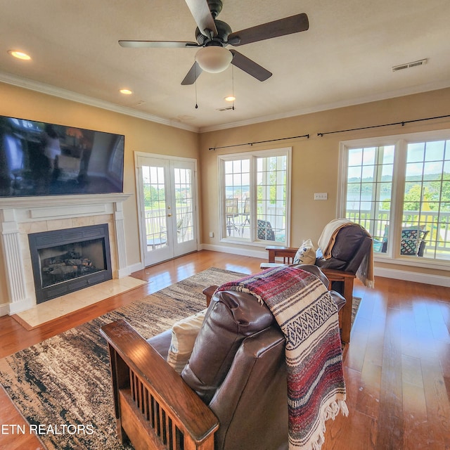 living room featuring ceiling fan, crown molding, wood-type flooring, and a fireplace