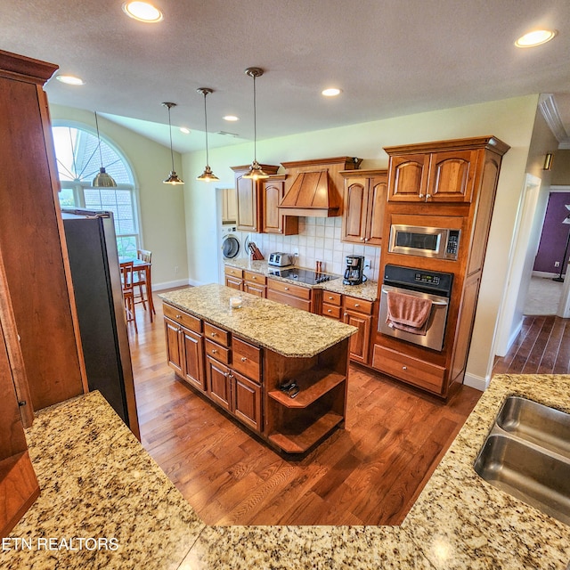 kitchen with custom exhaust hood, washing machine and clothes dryer, dark hardwood / wood-style floors, and stainless steel appliances