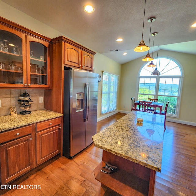 kitchen featuring vaulted ceiling, tasteful backsplash, light wood-type flooring, and stainless steel refrigerator with ice dispenser