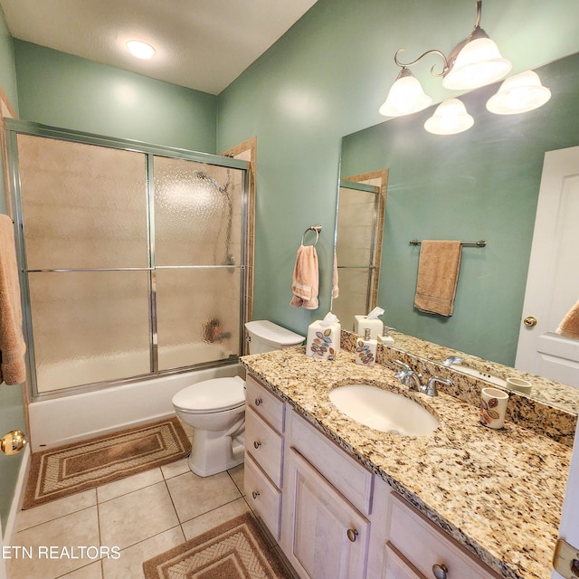 full bathroom with tile patterned floors, vanity, bath / shower combo with glass door, and toilet