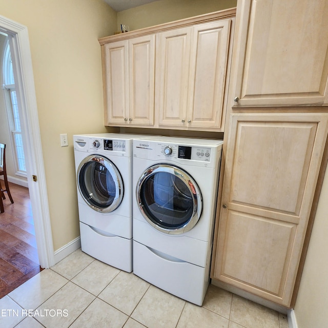 clothes washing area with light wood-type flooring, cabinets, and washing machine and clothes dryer