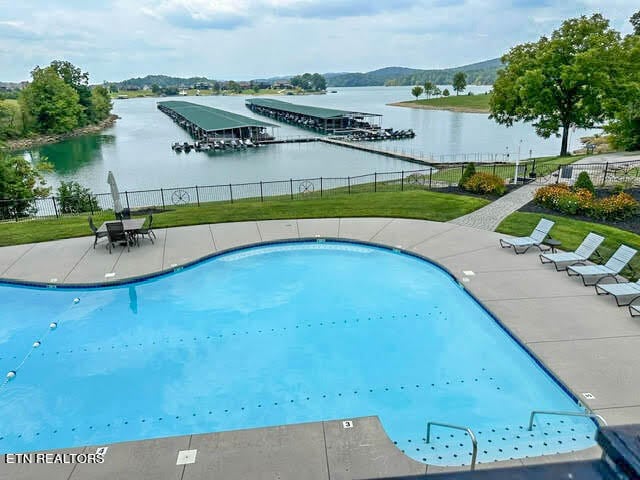 view of swimming pool featuring a lawn and a water view