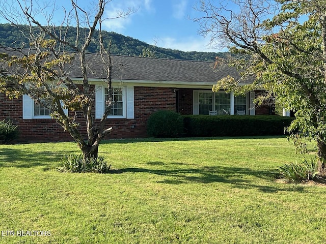 view of front of house with a mountain view and a front lawn