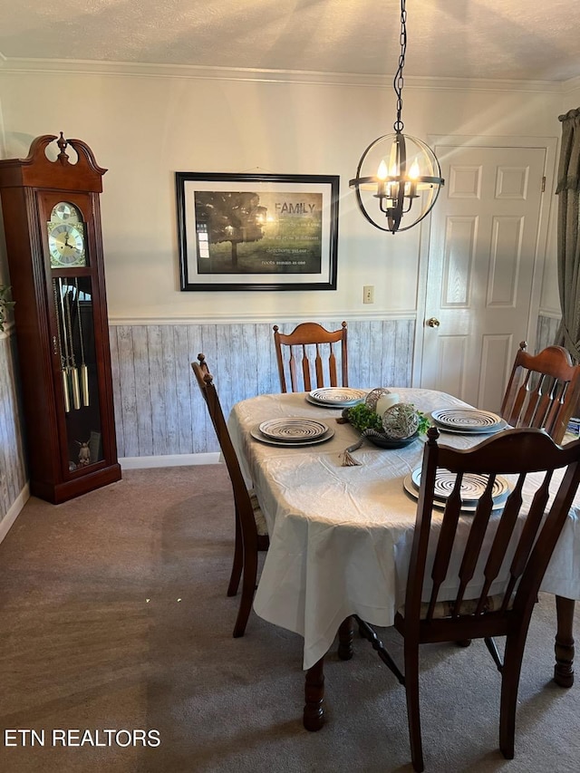 dining space featuring carpet flooring, a textured ceiling, wooden walls, a chandelier, and crown molding