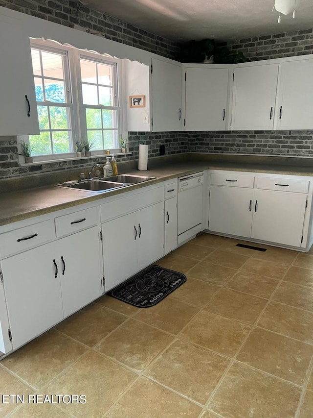 kitchen with white dishwasher, backsplash, sink, and white cabinets