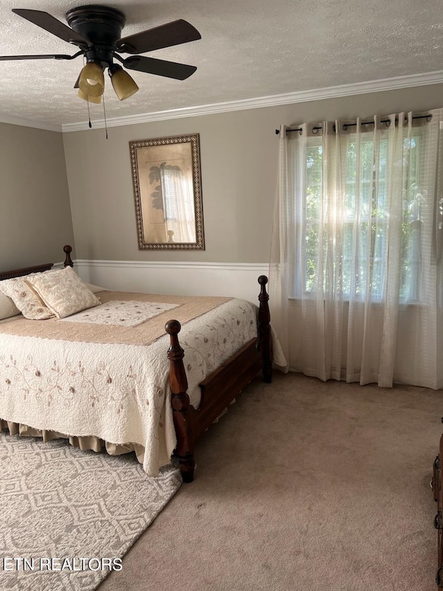 carpeted bedroom featuring ornamental molding, a textured ceiling, and ceiling fan