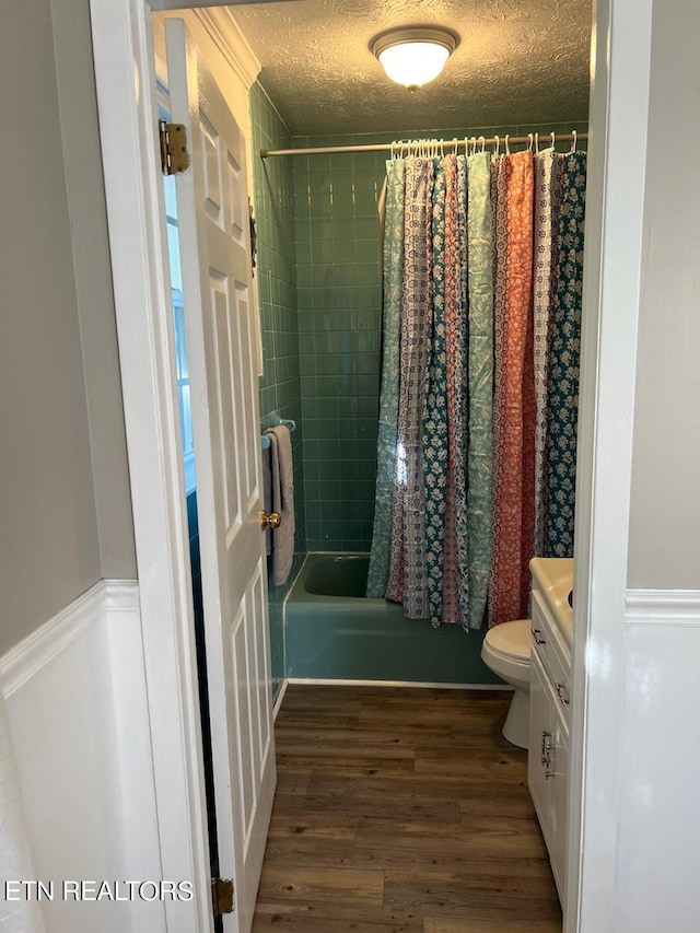 full bathroom featuring shower / bath combination with curtain, vanity, a textured ceiling, hardwood / wood-style flooring, and toilet