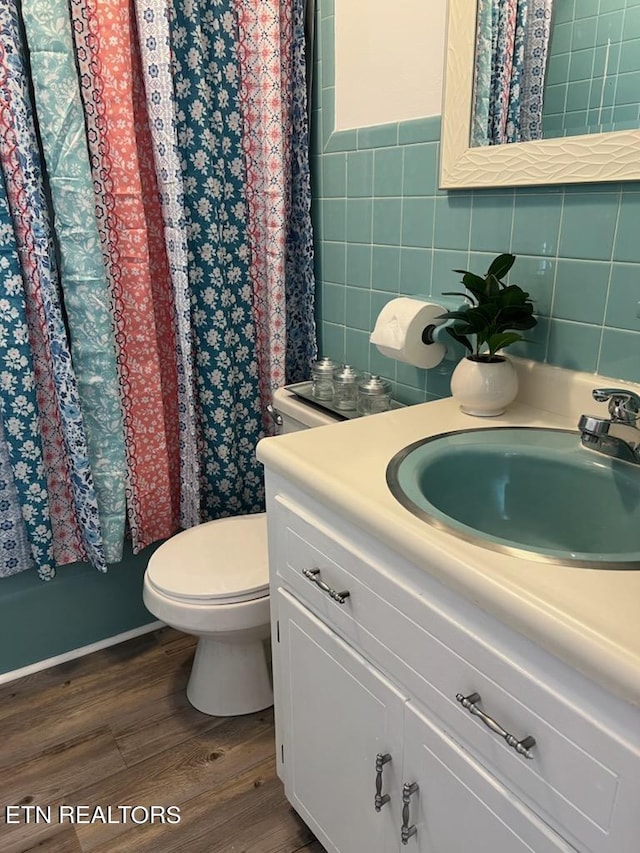 bathroom with vanity, toilet, curtained shower, tile walls, and hardwood / wood-style floors