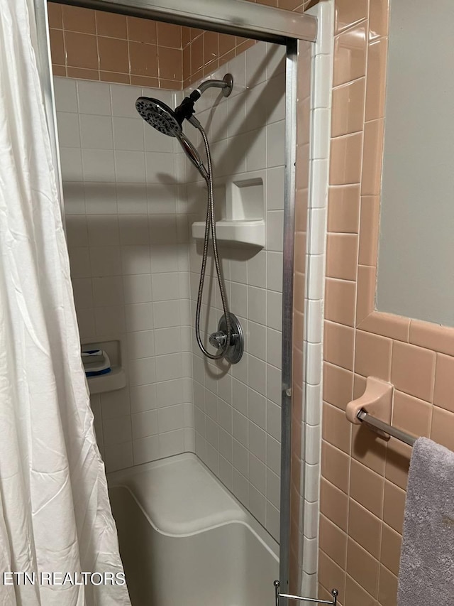 bathroom with tile walls and shower / tub combo with curtain