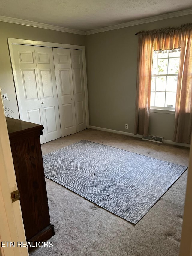 unfurnished bedroom featuring a closet, crown molding, carpet flooring, and a textured ceiling