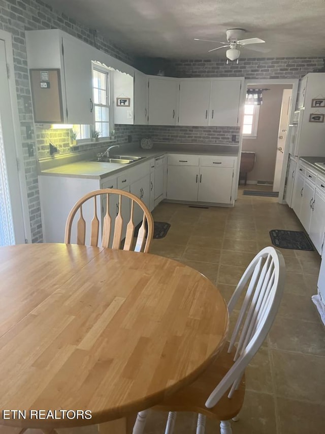 kitchen with dark tile patterned floors, ceiling fan, backsplash, and white cabinets